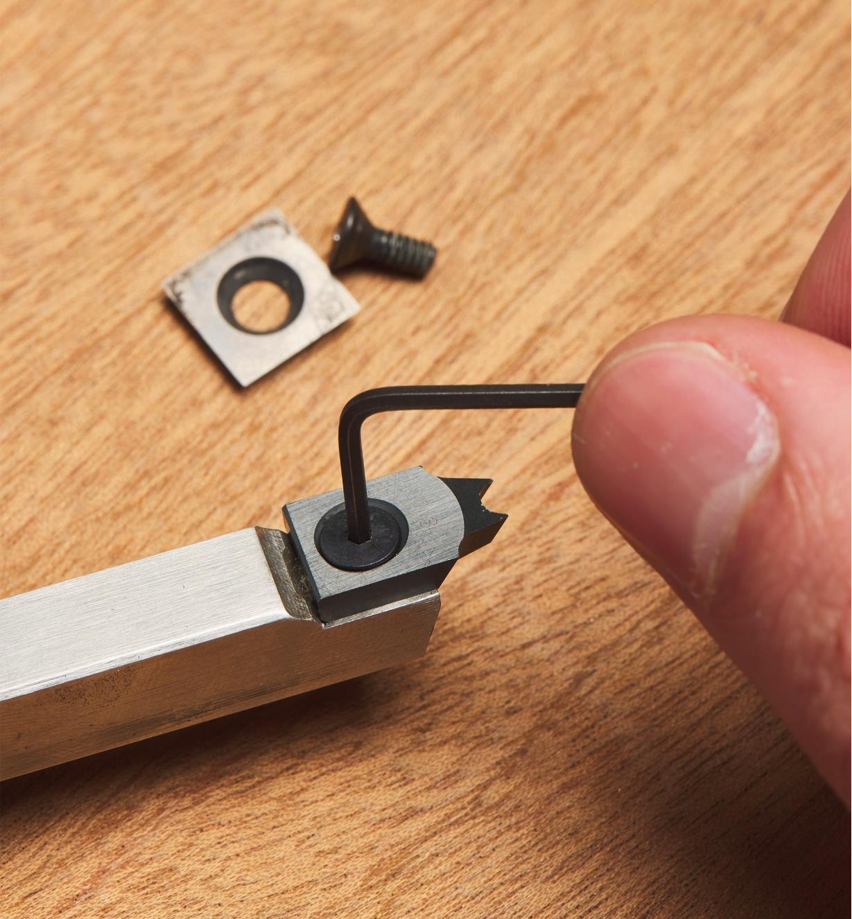 Using a screwdriver to tighten the screw of the negative-rake beading cutter