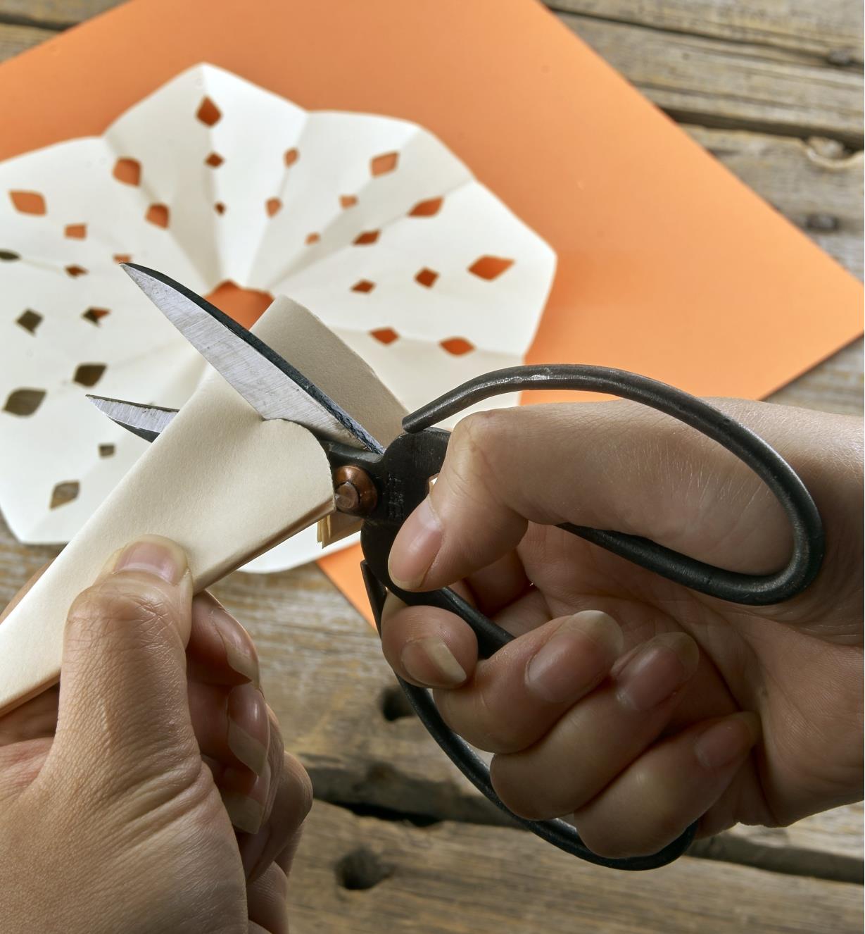 Thick paper being cut with traditional Chinese scissors