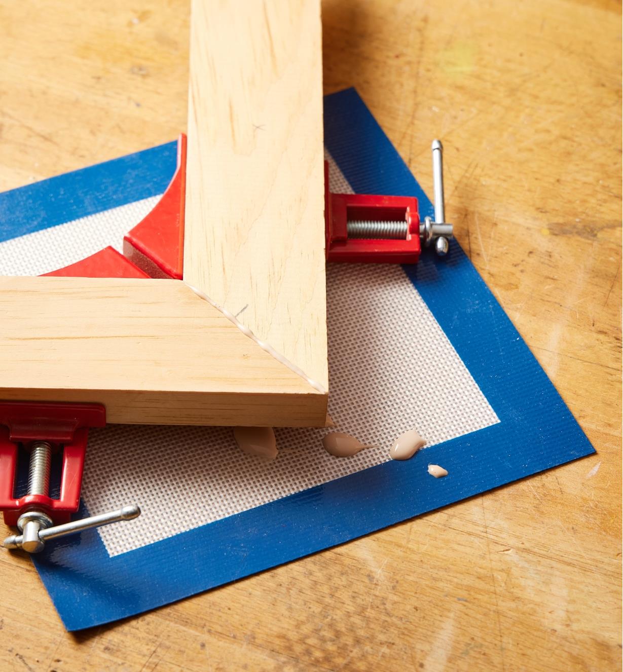 A clamped frame and drops of glue on a silicone mat