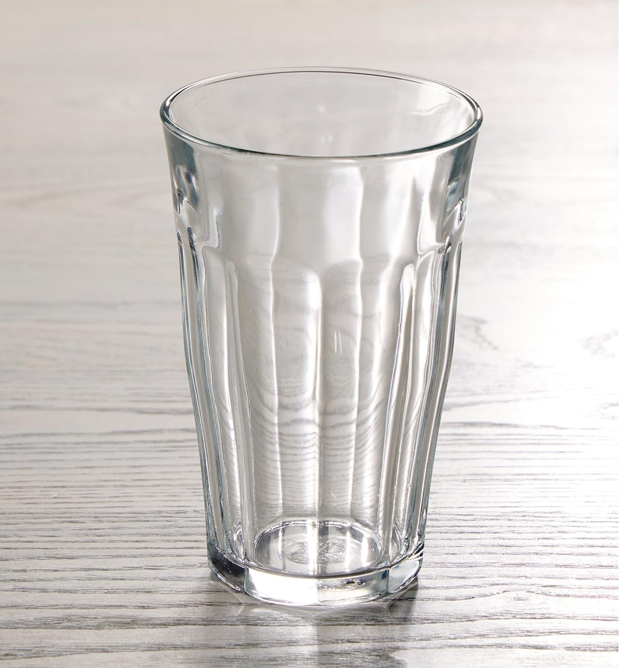 An empty 500ml Duralex Picardie glass placed on a wooden tabletop, backlit to show the fluted design