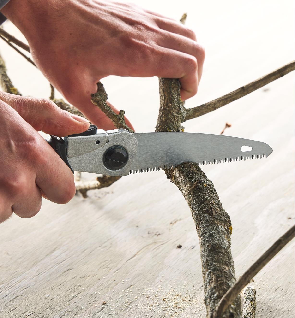 Using the folding pocket saw with the 11 tpi blade to cut a branch