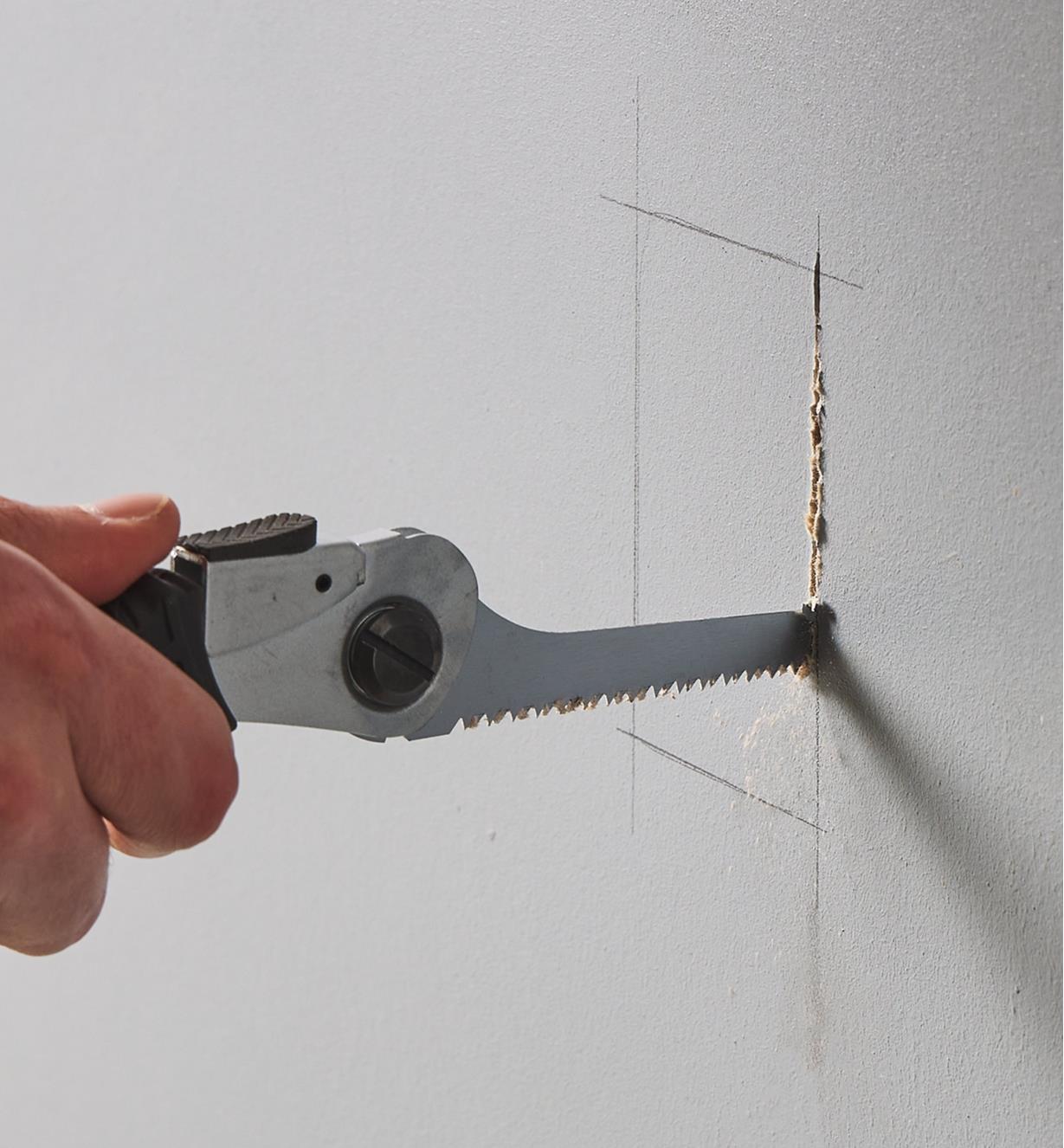 Using the folding pocket saw with the 10 tpi keyhole blade to cut a hole in a piece of drywall