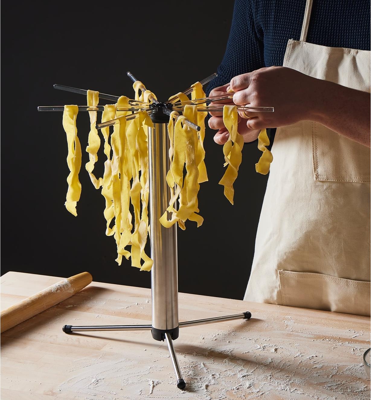 Draping pasta onto the Collapsible Pasta Drying Rack to dry