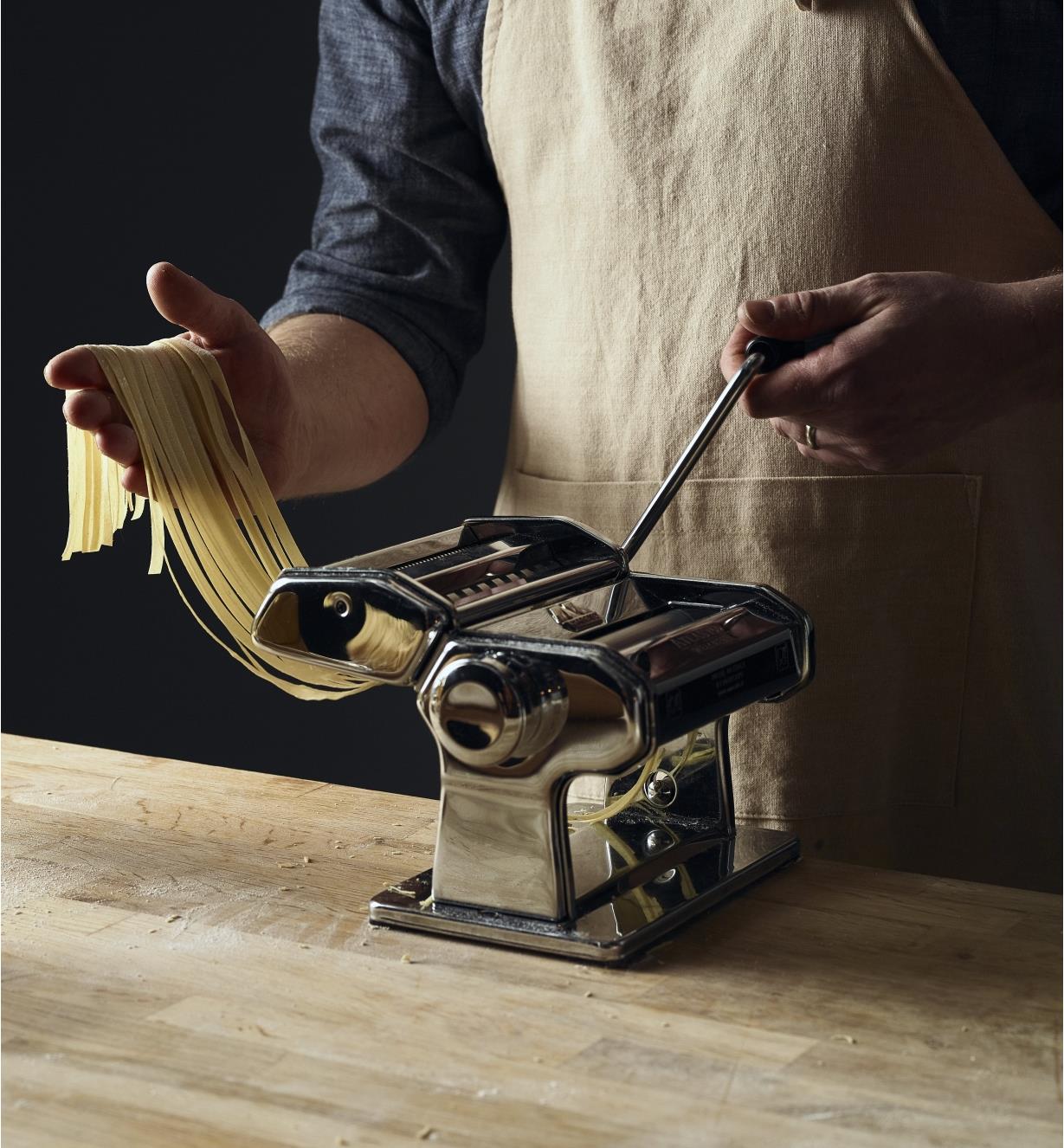 Personne préparant des fettucine à l’aide d’une machine à pâtes Marcato