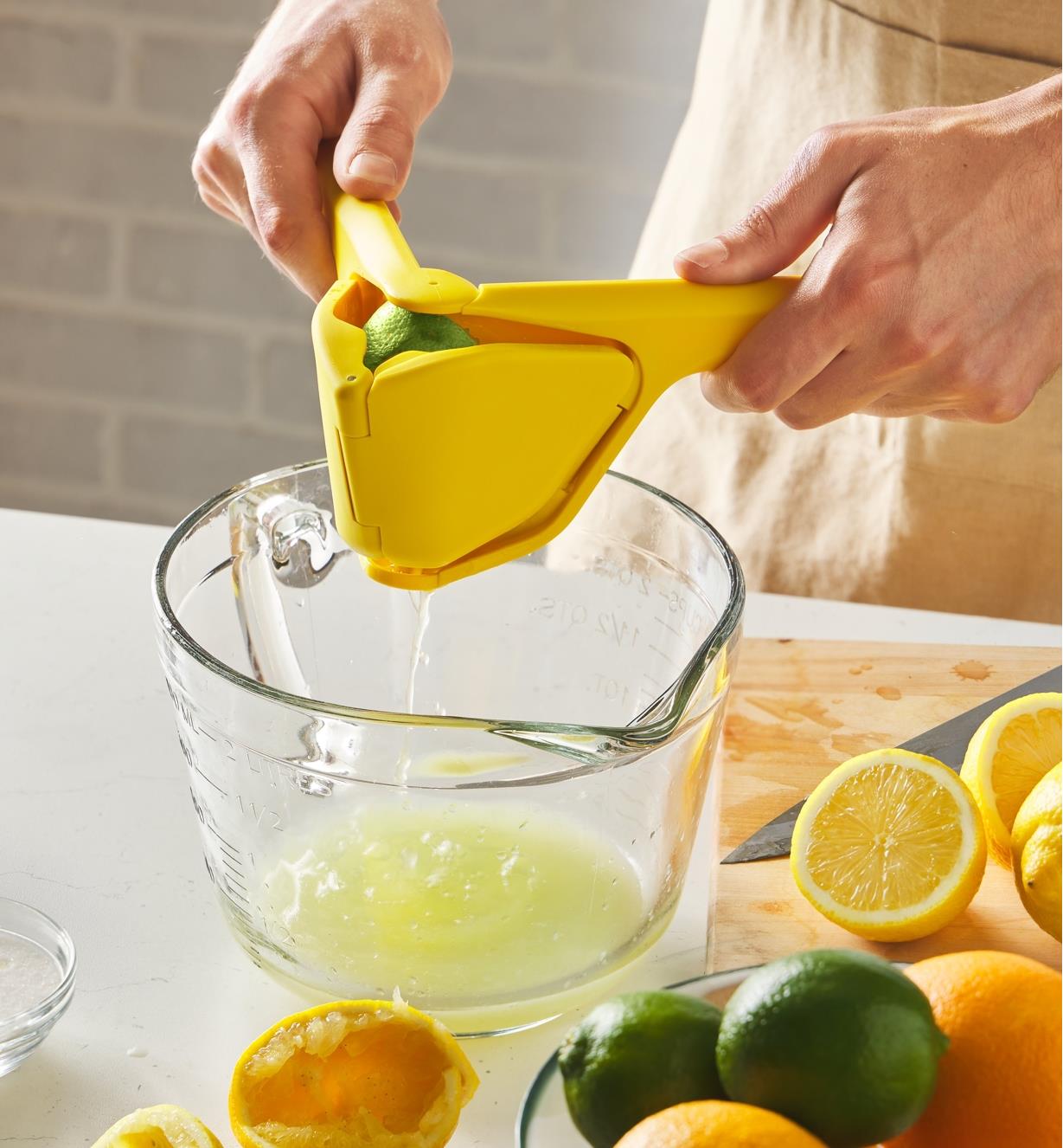 A lime being squeezed in a juicer over a measuring cup
