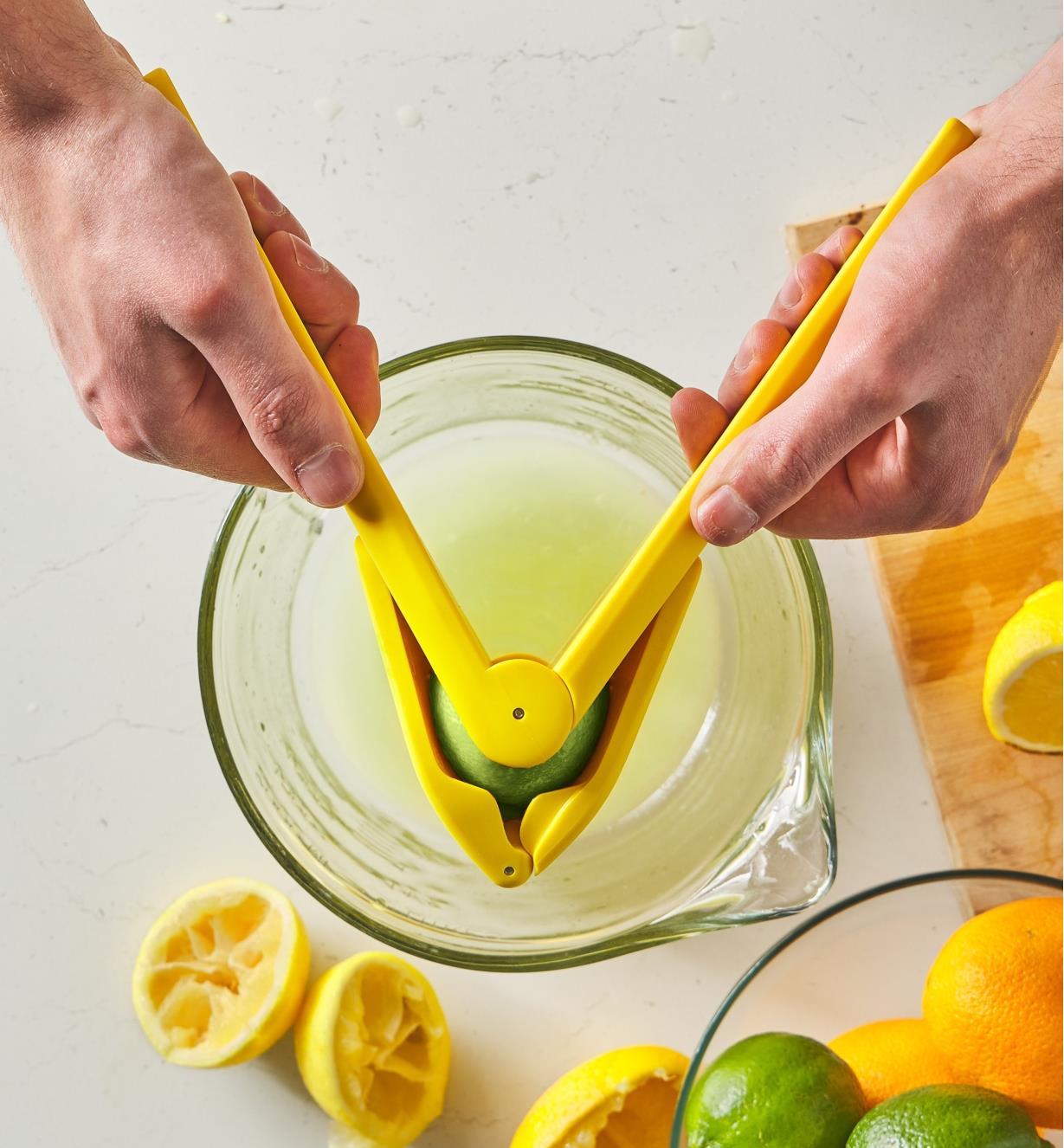 Pressing a lime in a juicer above a large measuring cup