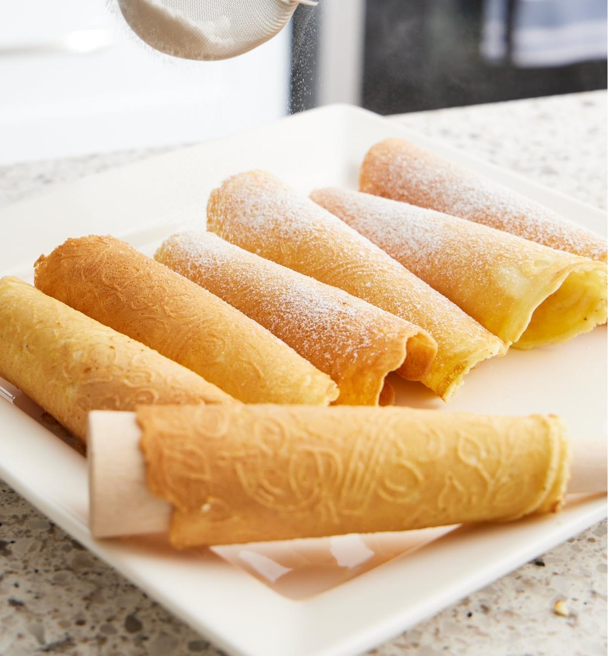 The warm krumkake cookie rolled around a wooden cone to create the hollow cone-shape
