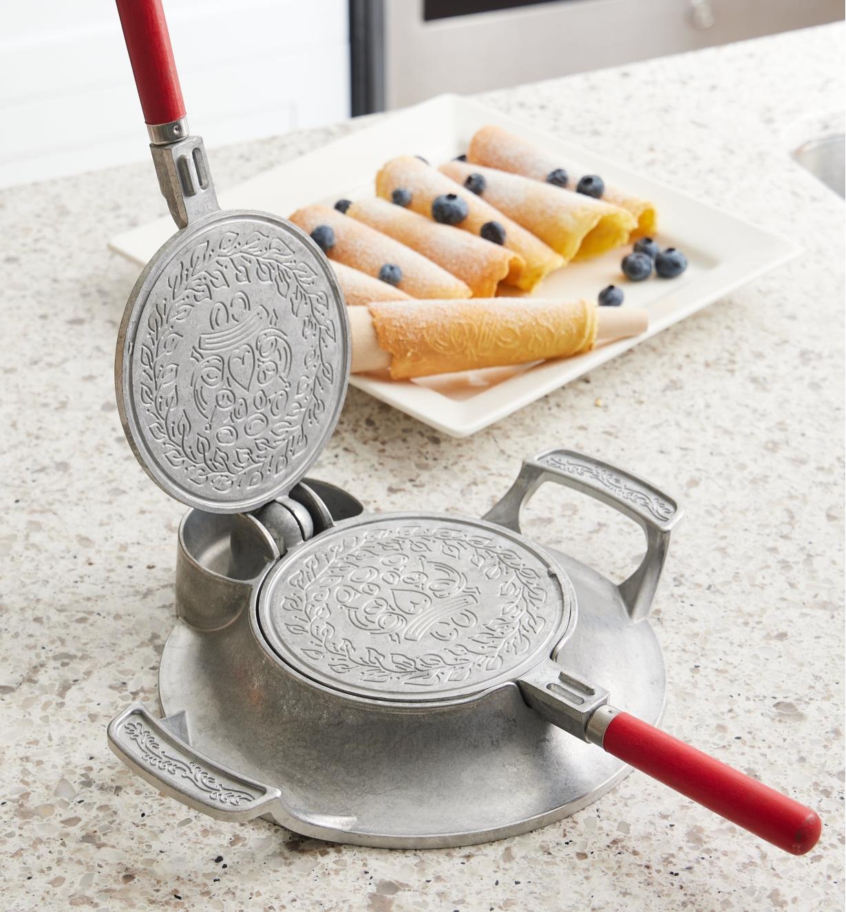 The krumkake and pizzelle iron with open griddle plates showing the embossed design