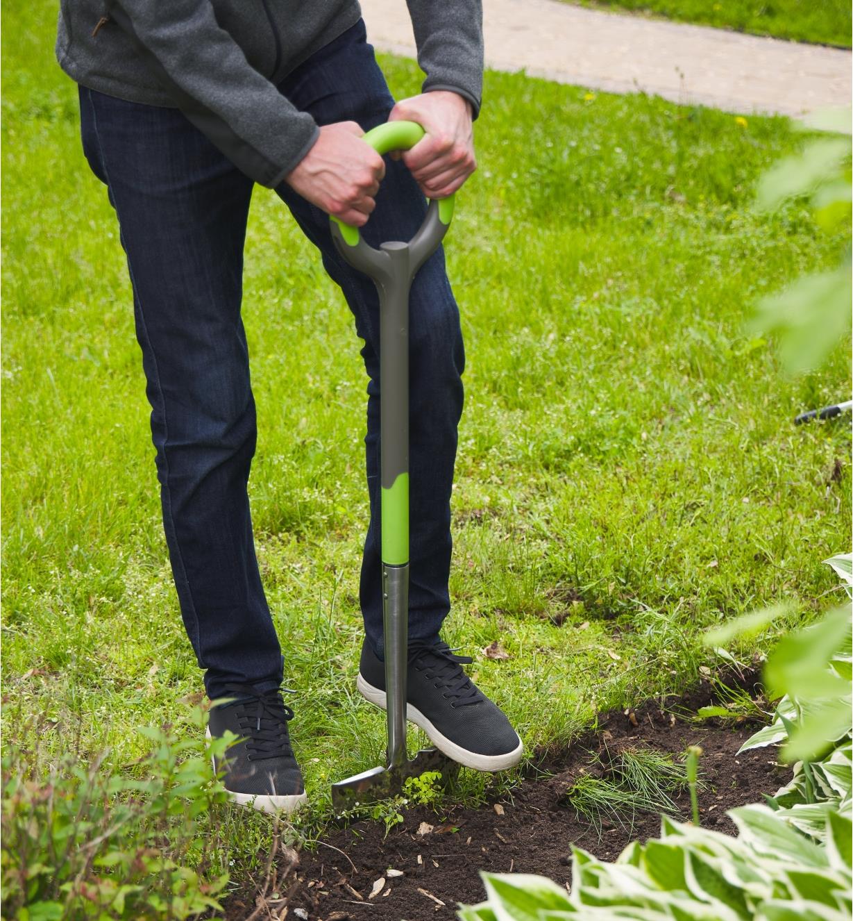 A preson cuts the edge of a garden using the Radius ergonomic edger