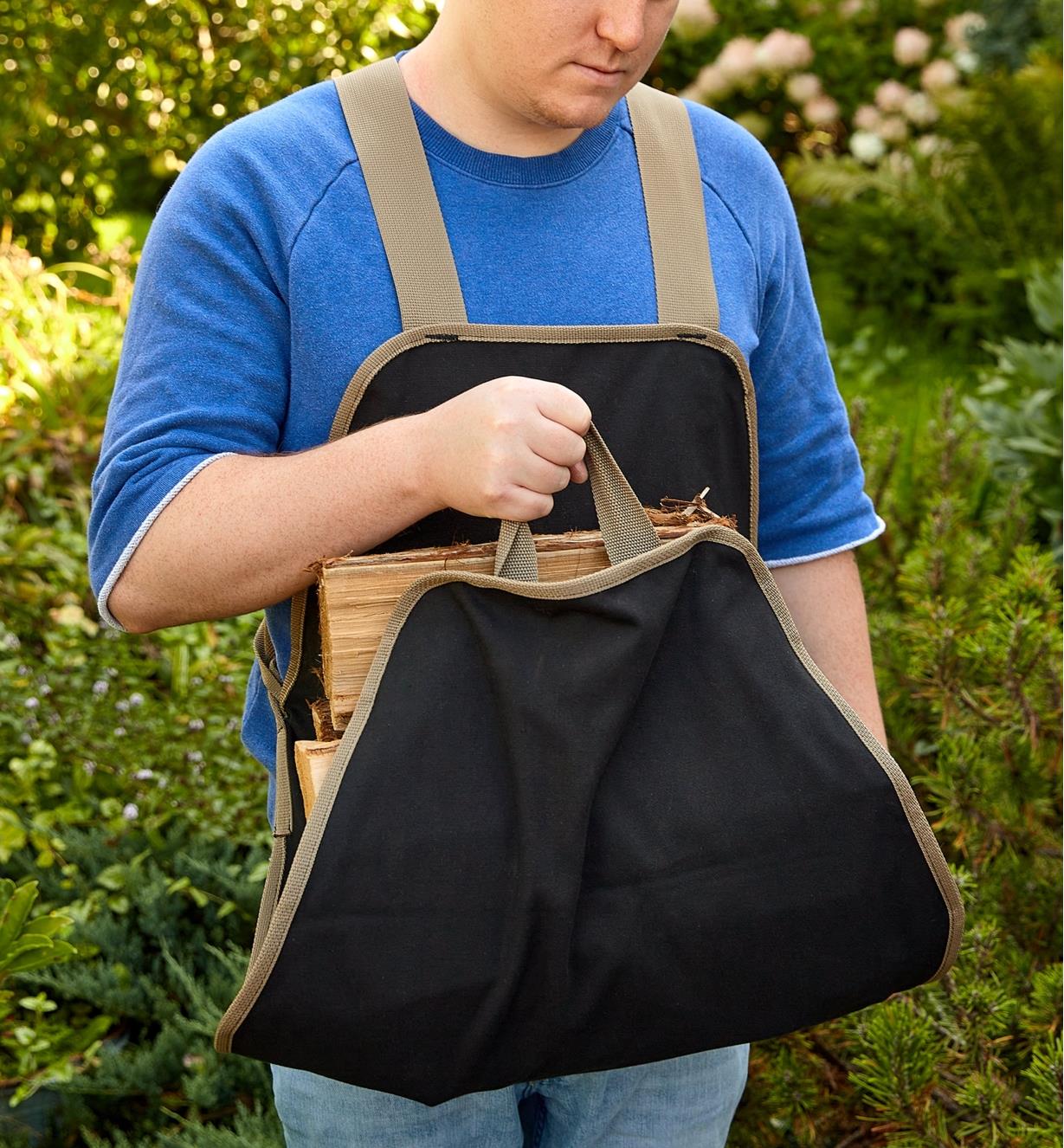 Front view of a man carrying firewood in the apron tote
