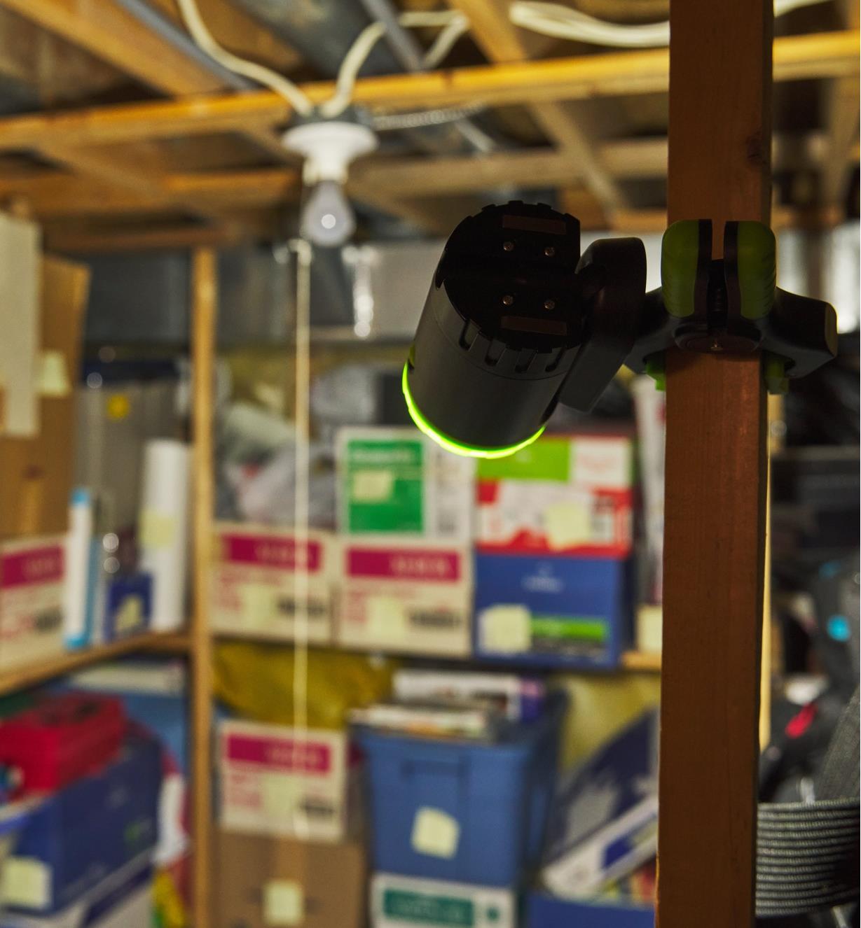 A rechargeable clip light mounted with the clamp base on a post to light a basement storage area
