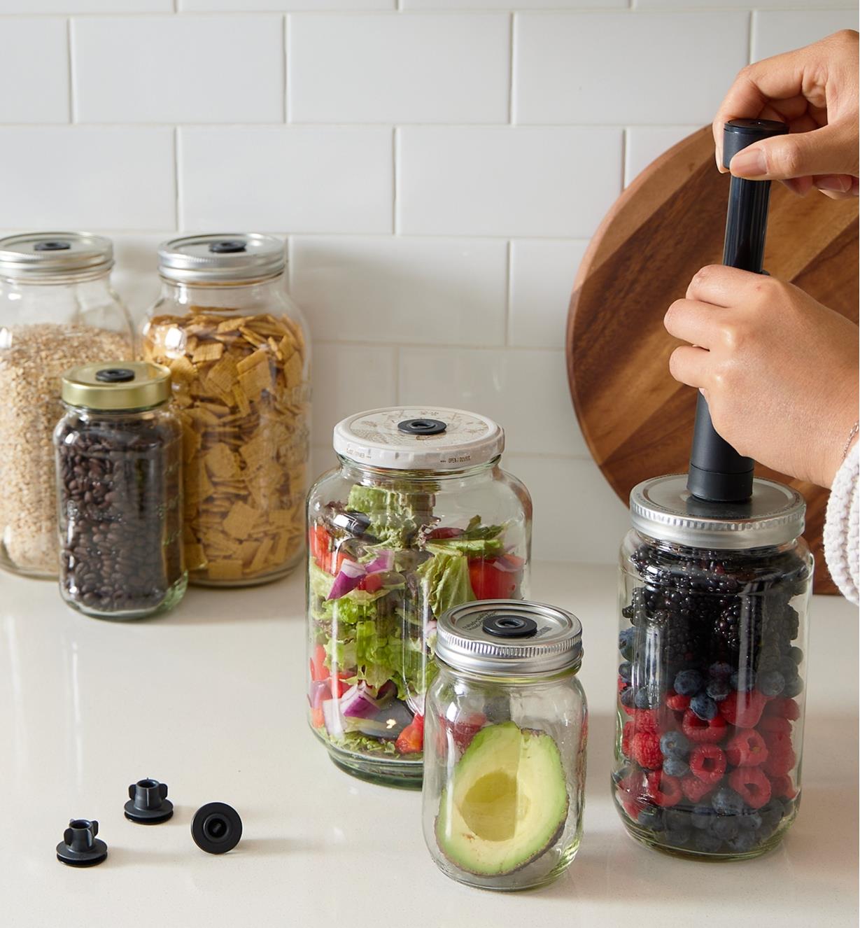 Half an avocado, berries, oats, cereal and other foods stored in jars using the Airtender system