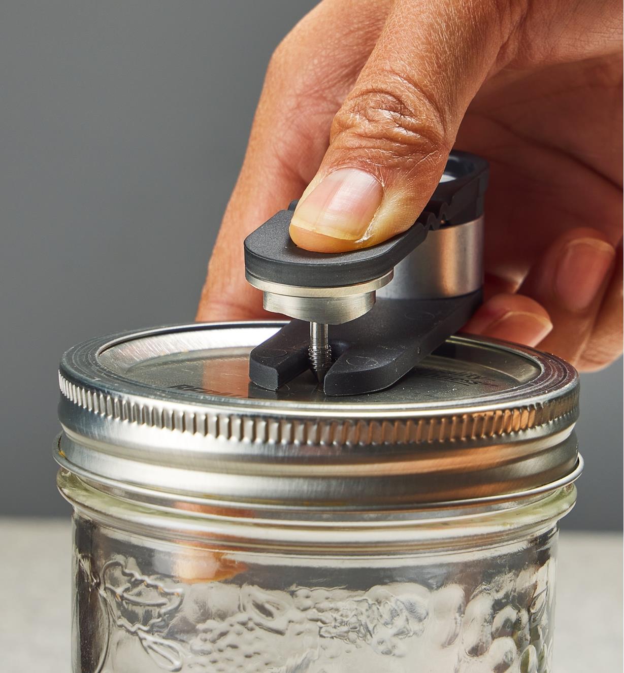 Using a tool included with the Airtender system to punch a hole in the lid of a Mason jar