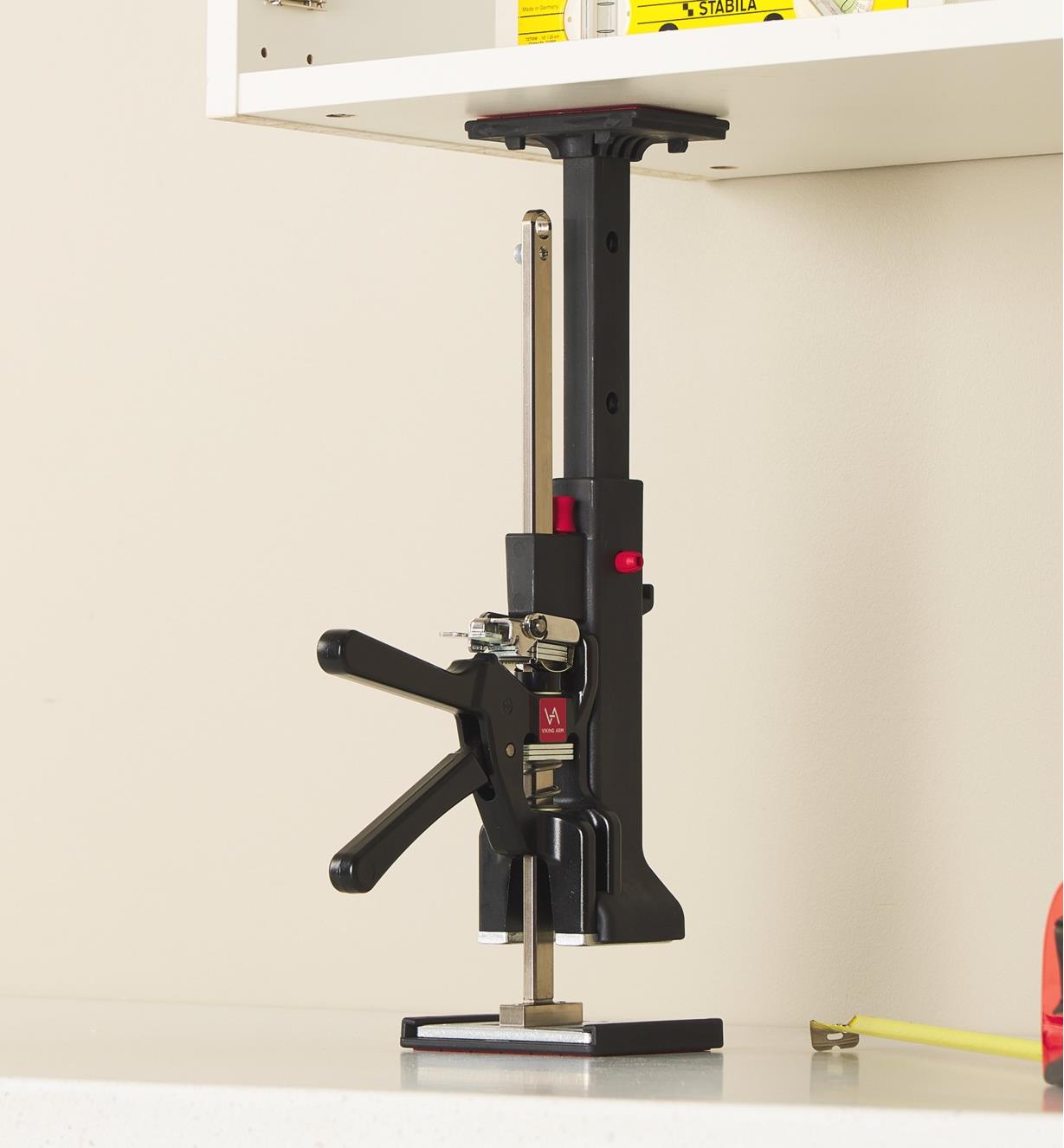 A Viking Arm jack being used with a cabinet installation kit to raise an upper cabinet into position
