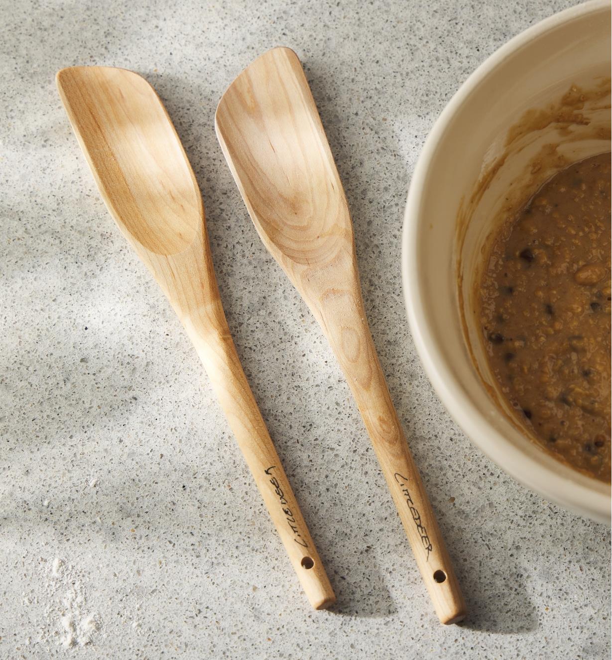 Deux cuillères-spatules en érable à côté d’un bol à mélanger sur un comptoir