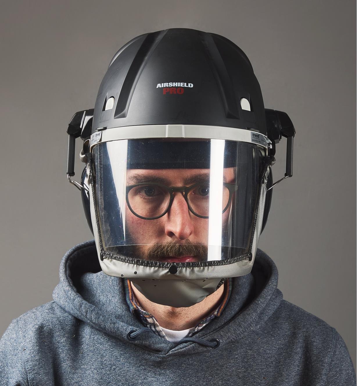 A man wears a Trend Airshield Pro full-face shield with the attached Ear Defenders against the ears