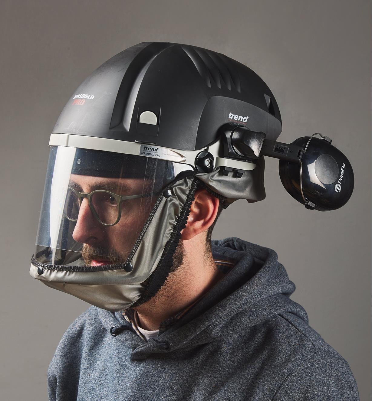A man wears a Trend Airshield Pro full-face shield with the attached Ear Defenders swung backward away from the ears