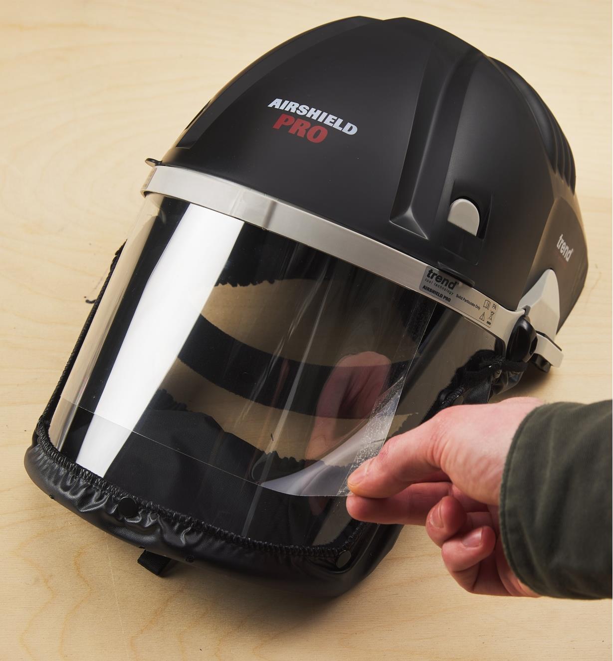 Removing a peel-and-stick film overlay from a visor