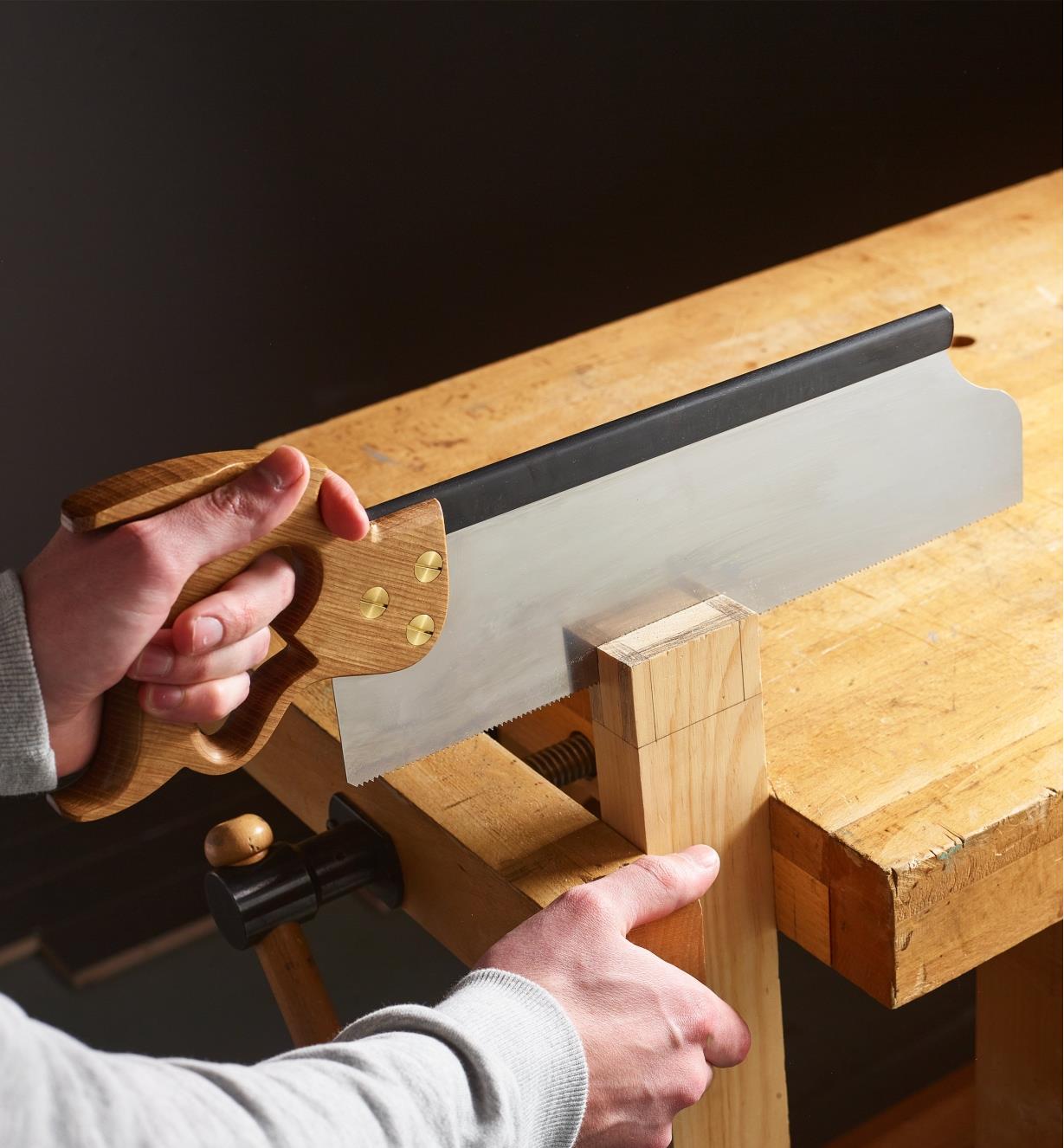 Sawing the end of a wooden board with a tenon saw