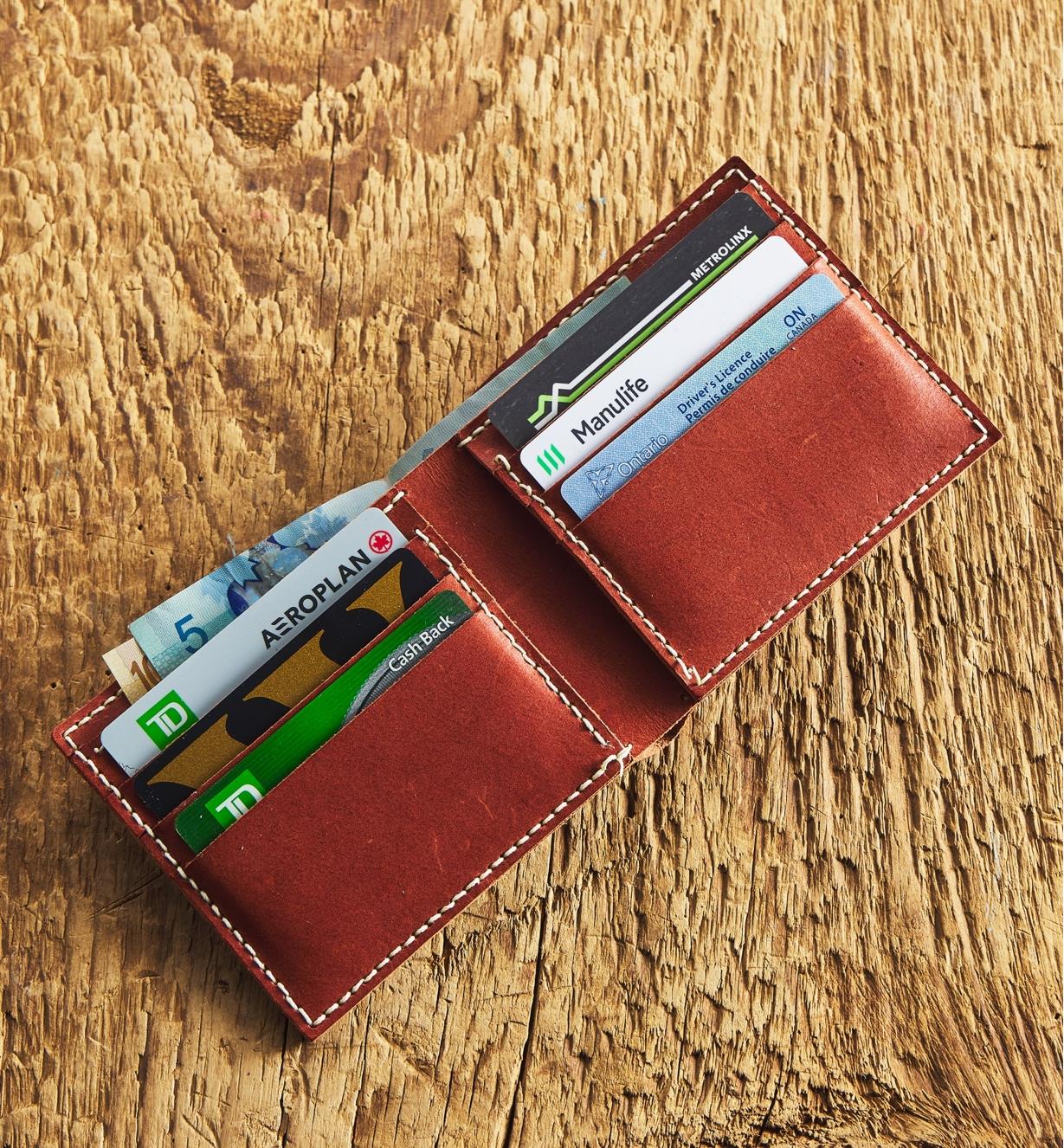 An open leather wallet with six cards and cash
