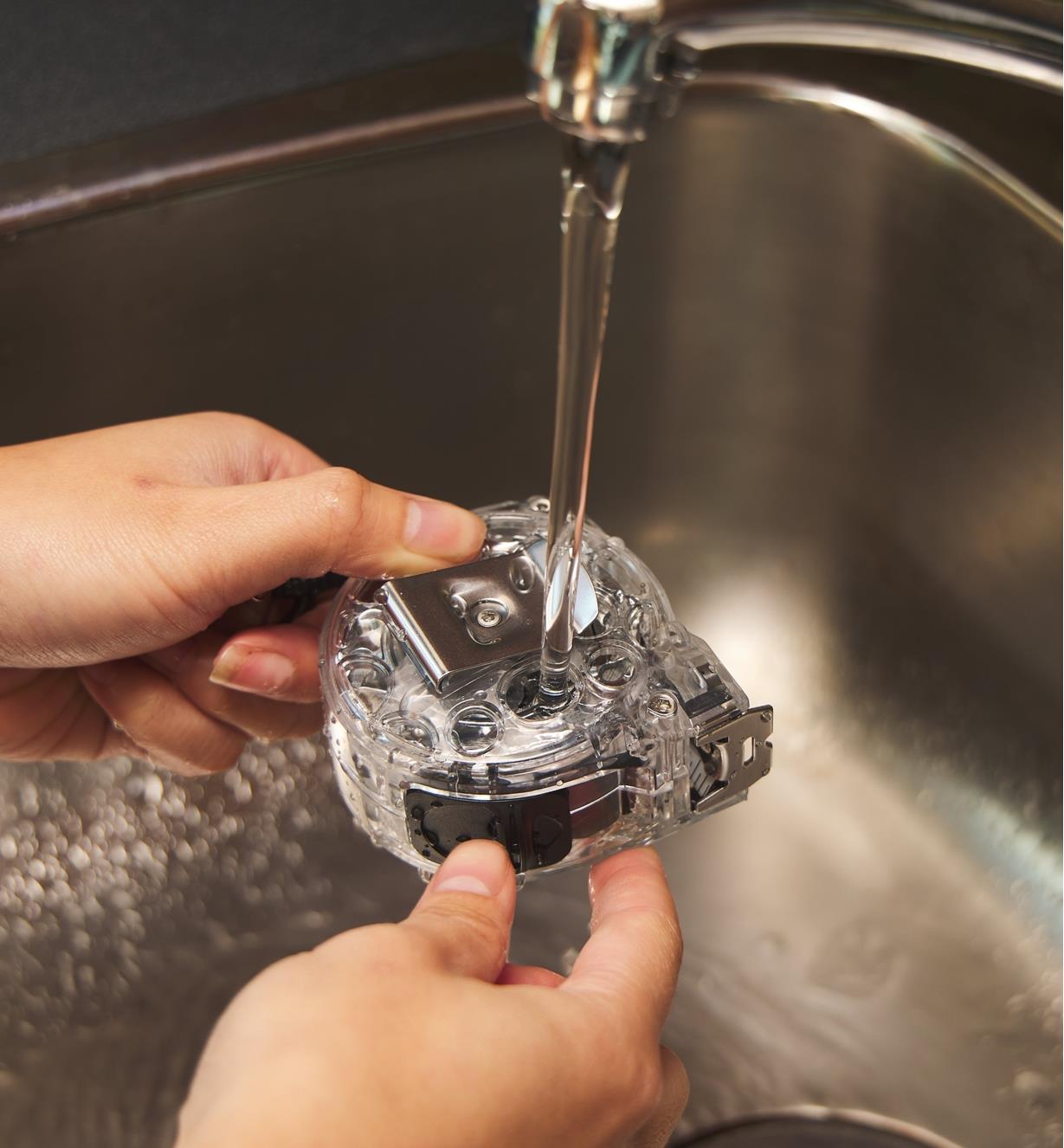 Rinsing a washable tape measure clean under a faucet