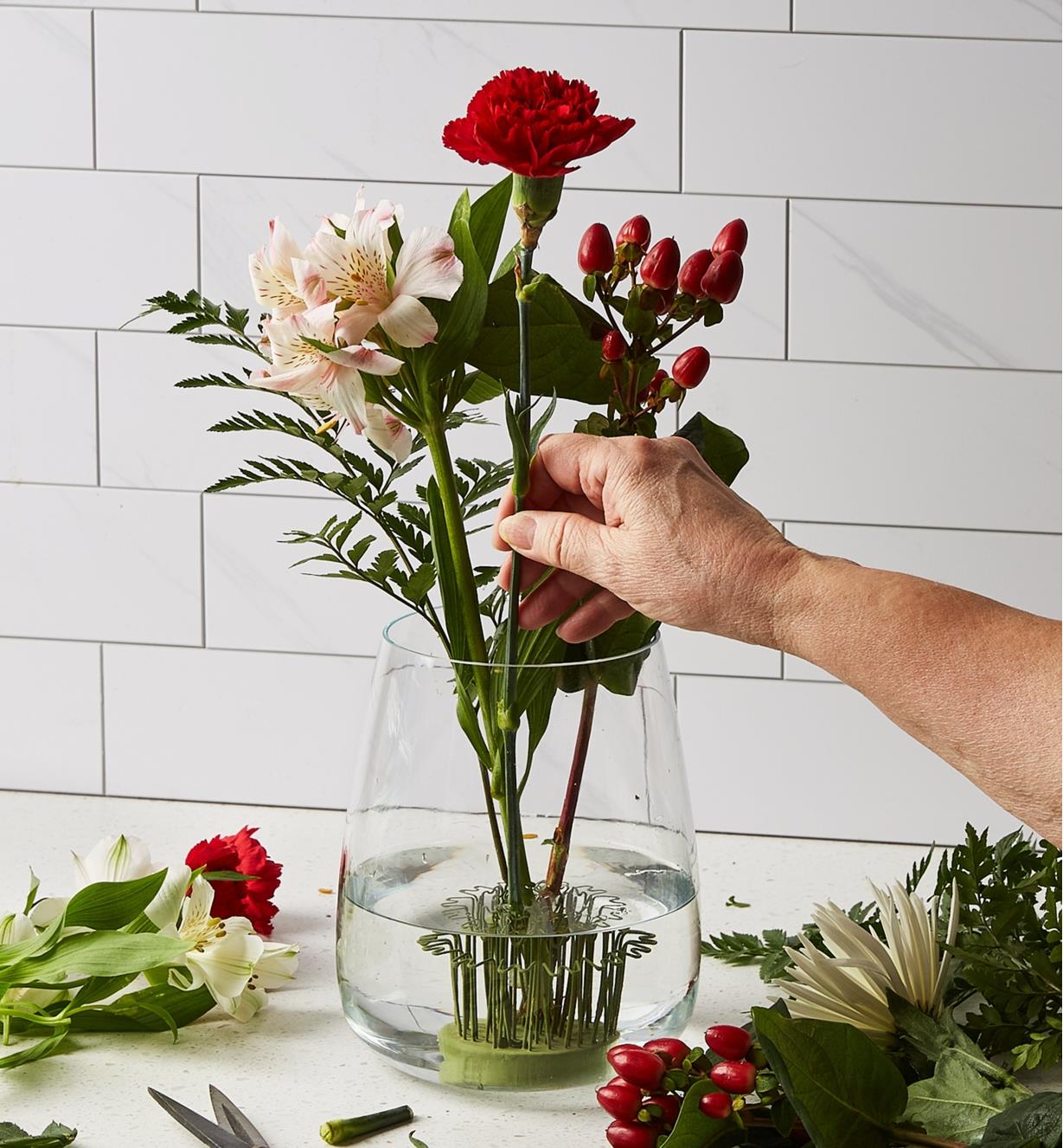 Arranging flowers in a Blue Ribbon flower holder in the bottom of a glass vase