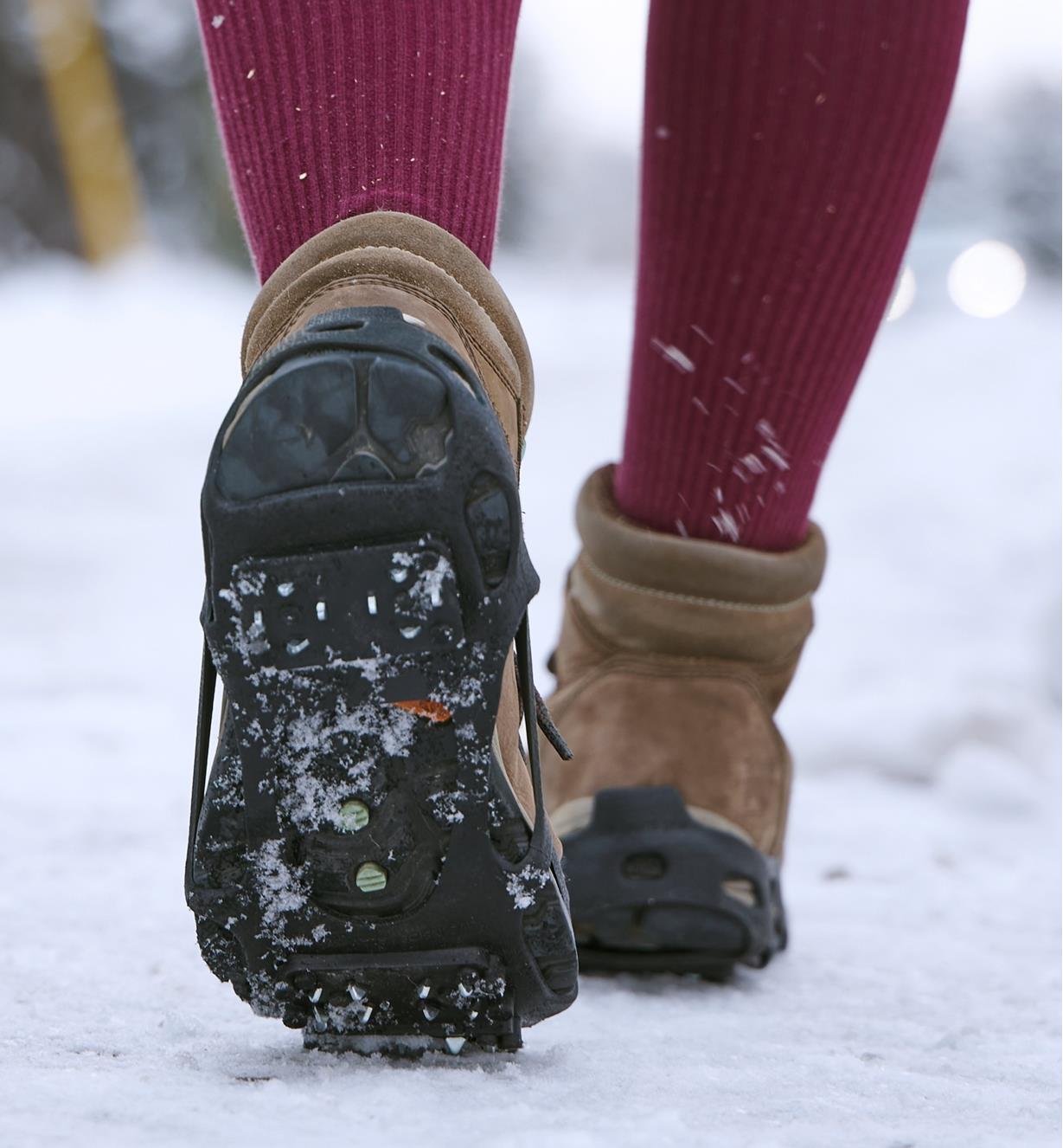 A person wears ice cleats over a pair of boots when walking over snowy ground