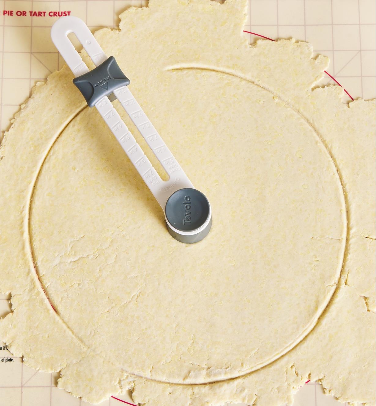 A pastry cutter positioned in the center of a circle of pastry dough