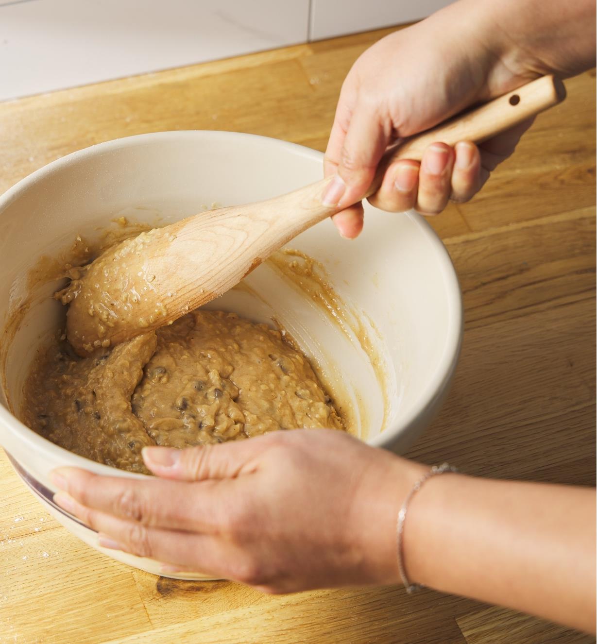 Using a slanted pot scoop to scrape batter from the sides of a mixing bowl