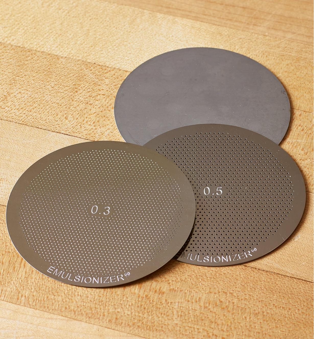 Trois disques en acier inoxydable déposés sur un comptoir.