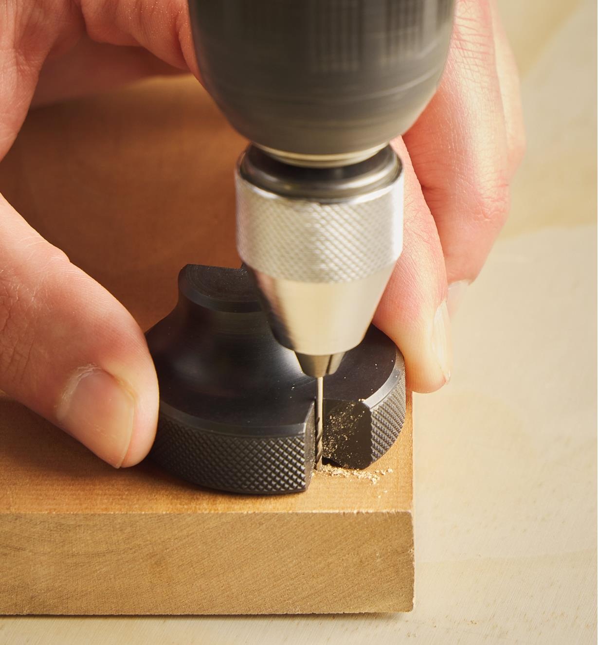 Using a drill and a pocket drilling guide to drill a hole near the corner of a wooden board
