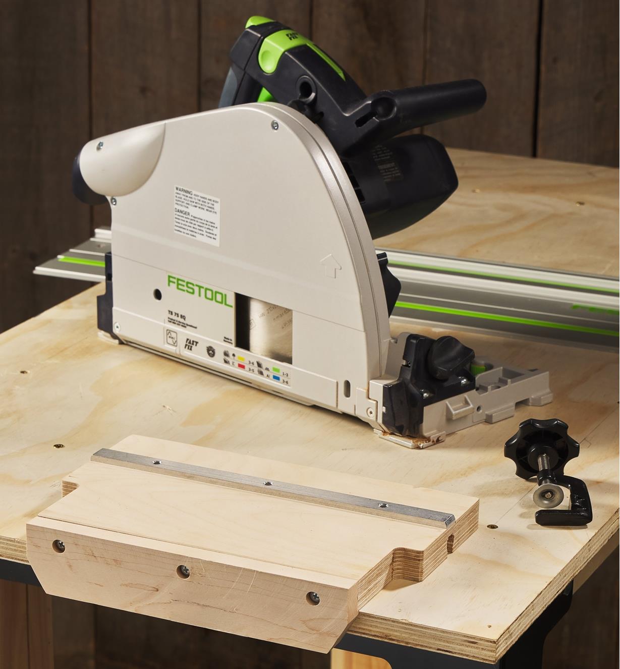A track saw alignment jig set on a workbench next to a track saw and guide rail