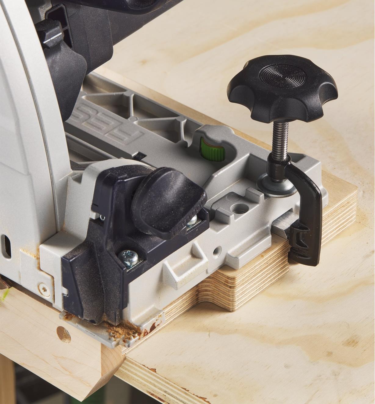 A track-saw guide clamp holds a track saw to a trimmed track saw alignment jig as its blade is reset