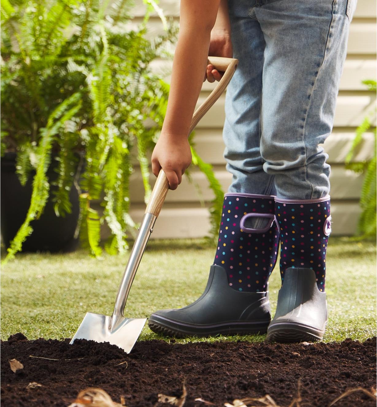 A child digs into soil with the children’s digging spade