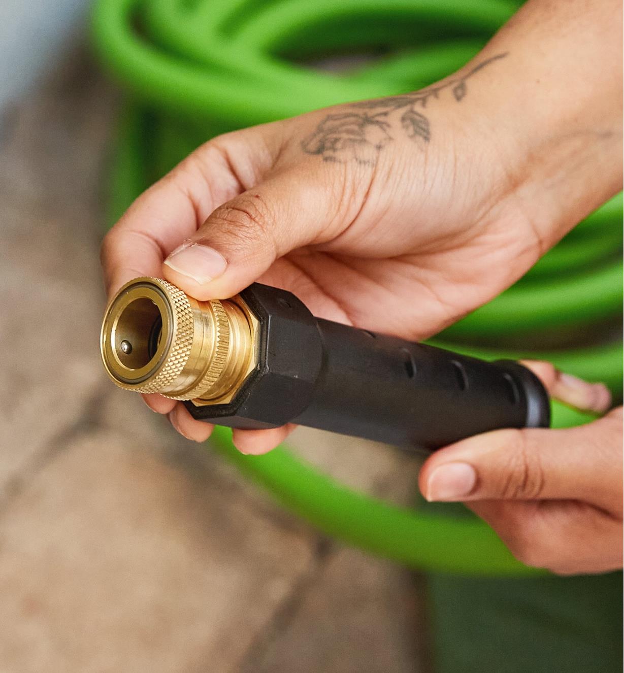 A gardener holds the end of a hose with a male hose-end quick coupler