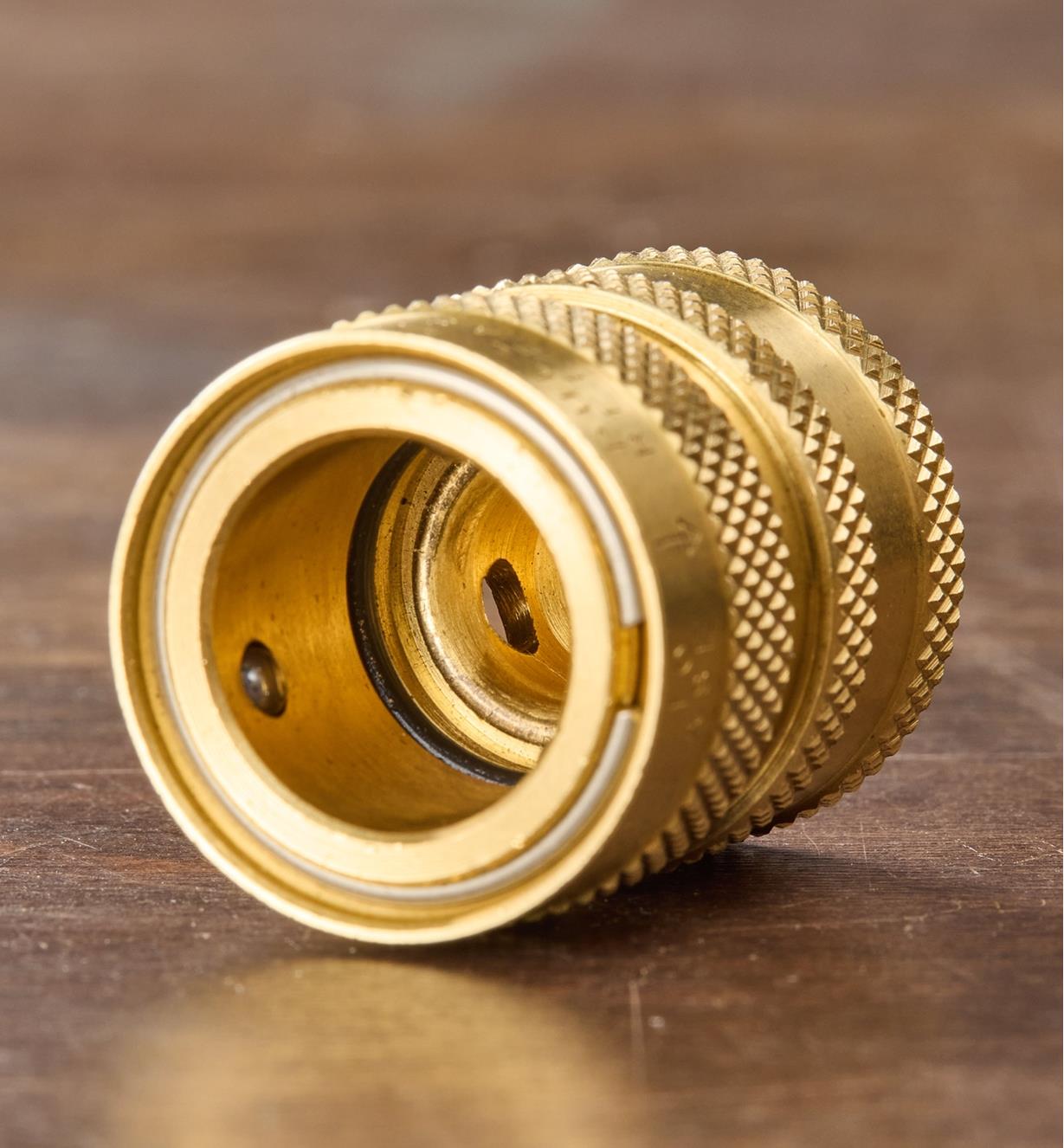A female brass coupler sits on a wood surface