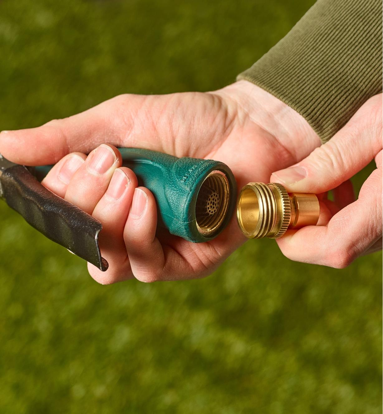 A gardener holds a nozzle in one hand with a male tool adapter in the other
