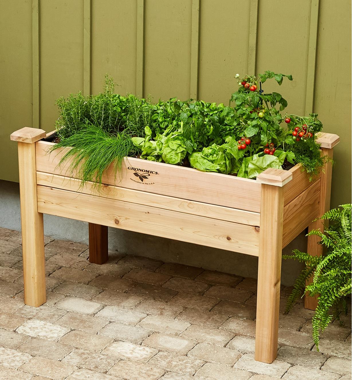 The elevated planter with a variety of vegetables growing in it