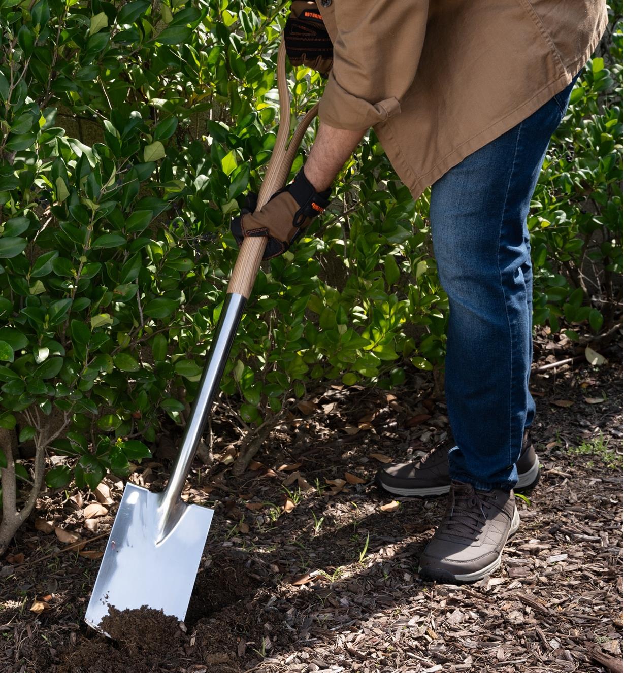 A gardener uses the border spade to move mulch