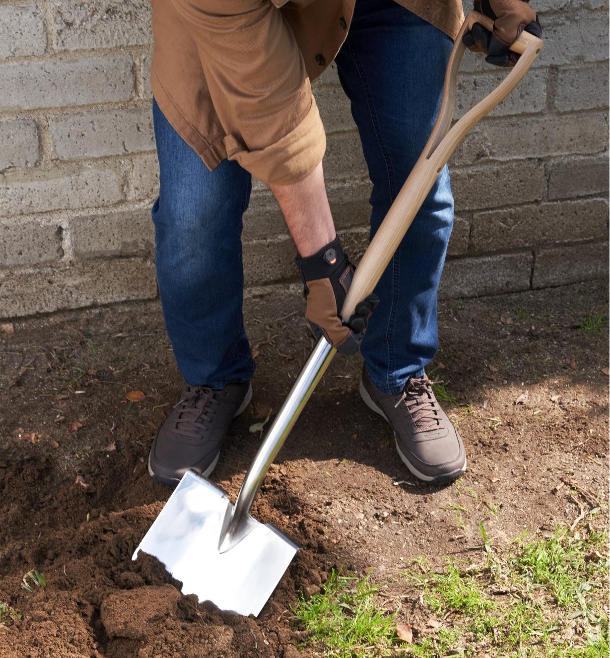 A gardener uses the stainless-steel shovel to dig into soil
