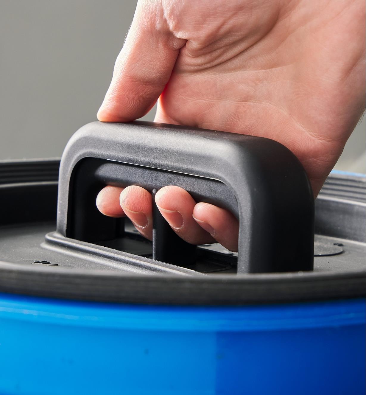 Pressing the release trigger on the handle of a bucket lid insert