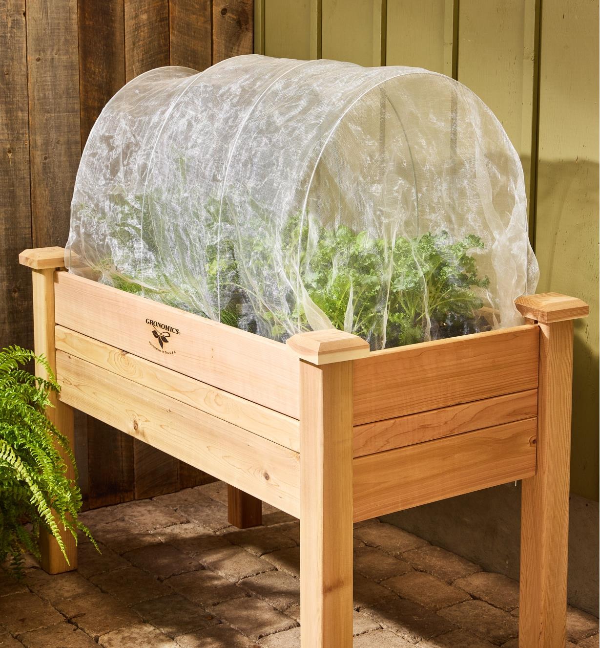 Insect protection fabric and garden hoops covering plants in a raised planter