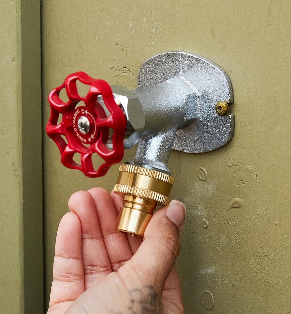 A tap-end quick connect being placed on an outdoor tap 
