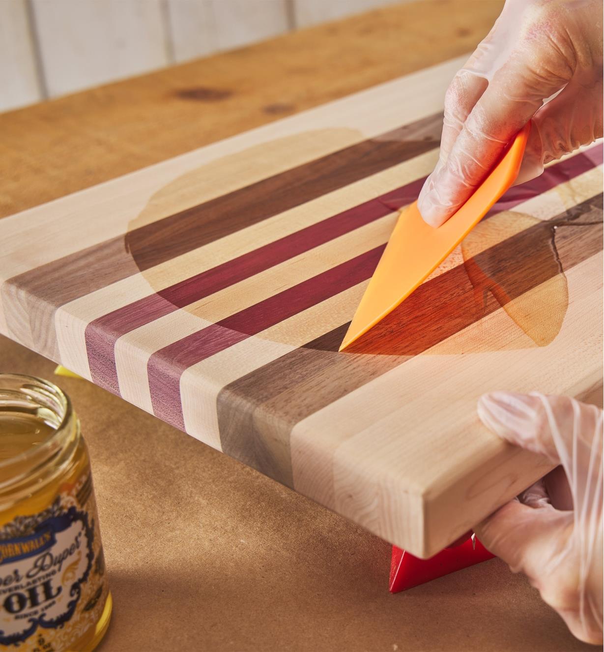 Using a spreader to apply Everlasting Oil to a cutting board