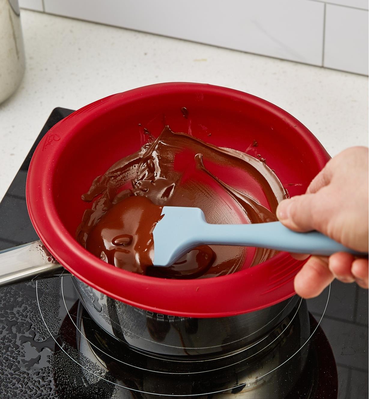 Personne brassant du chocolat dans un bol en silicone pour bain-marie