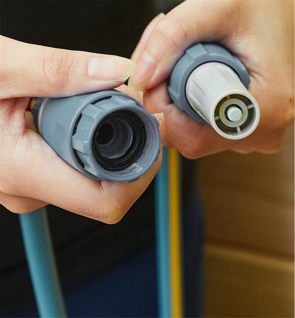 The hose’s spray gun is held in one hand and the connector end in the other hand