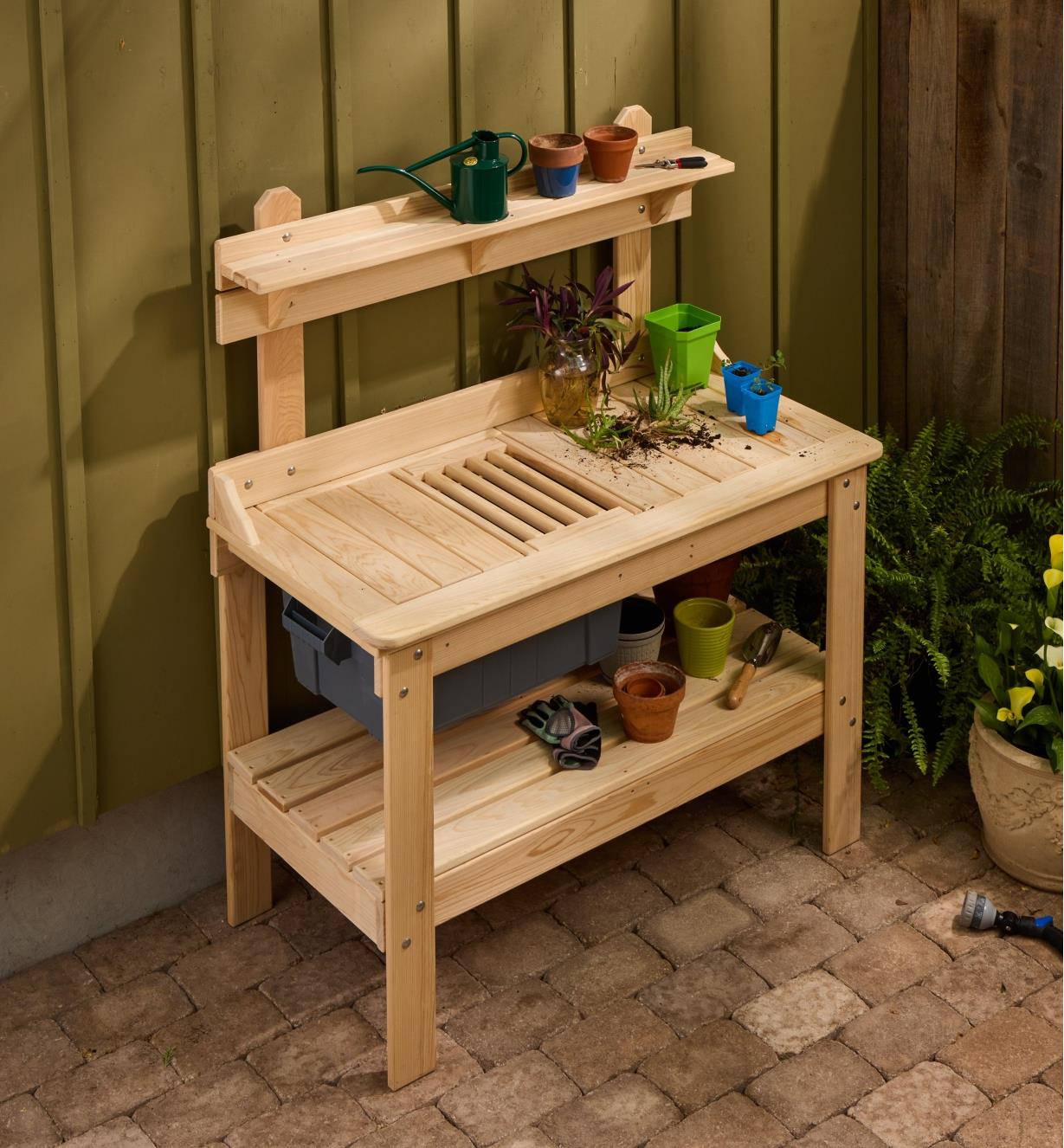 The cypress potting table set up on a patio with pots and other gardening items on it