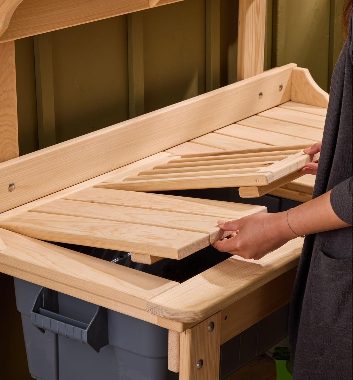 A gardener lifts the panels on the cypress potting table