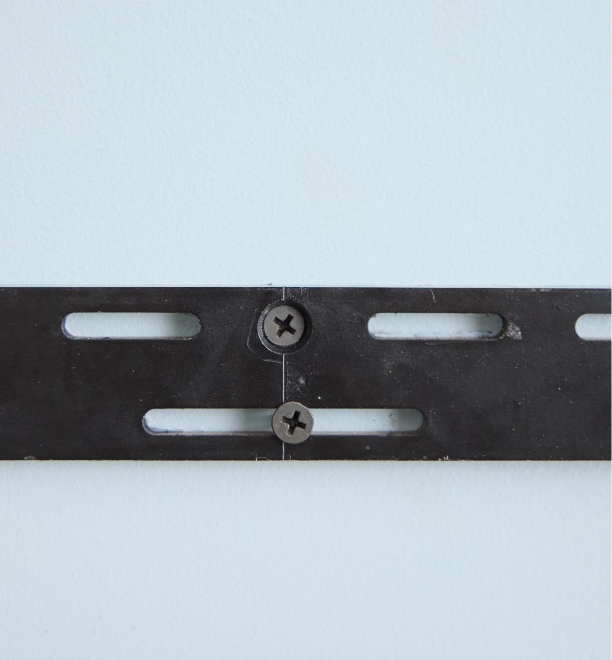 A shelf bracket attached to a wall with two screws