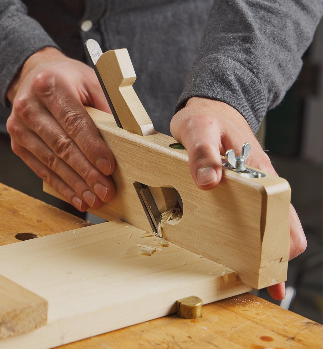 Personne utilisant un guillaume traditionnel en bois E.C. Emmerich pour parfaire l'épaulement d'une feuillure